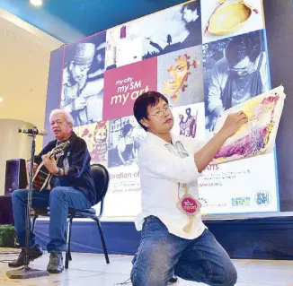  ??  ?? Tayo’y Mga Pinoy: Folk-rock singer and painter Heber Bartolome gives the audience a sample of his unique synthesis of rock, blues and Philippine ethnic rhythms, as Elito Circa paints during the event.