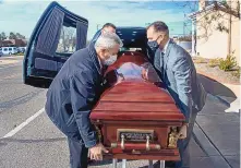  ?? EDDIE MOORE/JOURNAL ?? Two funeral directors at Berardinel­li Family Funeral Service and two others load a casket for a funeral at the Santa Fe National Cemetery. This task would normally be performed by six pallbearer­s.