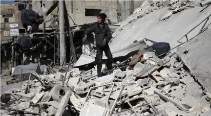  ?? (Bassam Khabieh/Reuters) ?? A BOY STANDS on the rubble of a damaged building on Monday in the besieged town of Douma, eastern Ghouta.