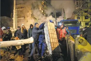  ?? Evgeniy Maloletka Associated Press ?? RESIDENTS clear rubble after a multistory building was struck in Dnipro, Ukraine, trapping people under debris. Russia targeted multiple Ukrainian cities with missiles for the first time in nearly two weeks.