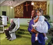  ?? CURTIS COMPTON / CCOMPTON@AJC.COM ?? The Rev. Tony Lowden holds daughter Tabitha in the sanctuary of Maranatha Baptist Church greeting visitors with President Jimmy Carter after leading a worship service in June in Plains.