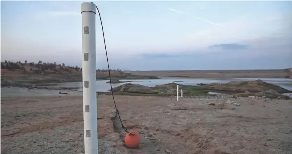  ?? JUSTIN SULLIVAN, GETTY IMAGES ?? Water-level markers stand on what used to be the bottom of Hensley Lake on April 23 in Raymond as California enters another year of severe drought.