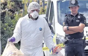  ??  ?? > Police officers gather evidence at Trem Y Garnedd, Bangor