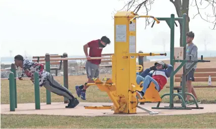  ?? MIKE DE SISTI / MILWAUKEE JOURNAL SENTINEL ?? People work out Wednesday at an exercise station near North Point Park on the Lake Michigan lakefront in Milwaukee. On the first full day after Gov. Tony Evers’ stay-at-home order to stop the spread of coronaviru­s, people were out taking advantage of the weather but not practicing social distancing.