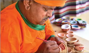  ??  ?? A man decorates a lamp with the name of Lord Ram on it ahead of the foundation stone laying ceremony of Ram Mandir in Ayodhya on 5 August, in Bikaner on Saturday. ANI