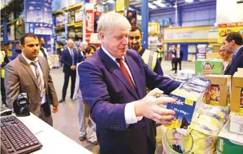  ?? Reuters ?? Britain’s Prime Minister Boris Johnson checks an item during a visit to Bestway Wholesale in Manchester yesterday.