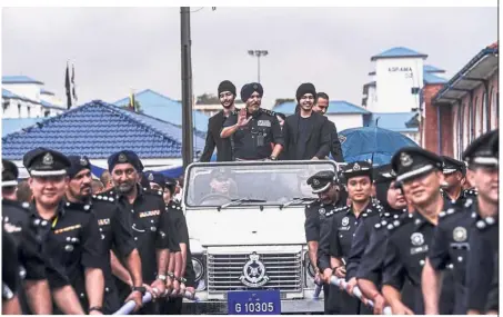  ?? — Bernama ?? Riding high: Comm Amar, with his sons, waving from a ceremonial vehicle at the Police Training Centre.