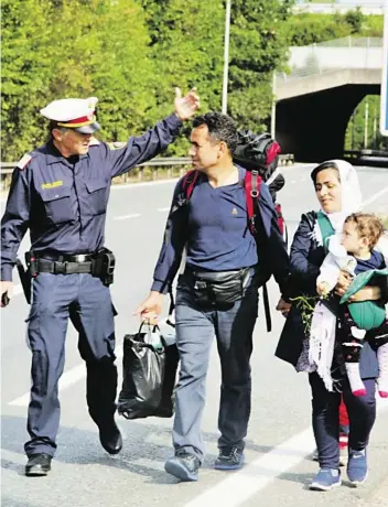  ?? BILD: SN/BERTHOLD SCHMID ?? Ein Polizist erklärt bei Salzburg-Nord einer Familie den Weg zum Salzburger Bahnhof. Die Flüchtling­e wollten nicht im Notquartie­r in Salzburg-Kasern bleiben.