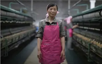  ??  ?? Kim Jong Sil, 35, stands in the Kim Jong Suk Silk Mill in Pyongyang where she has worked for 17 years. Her motto: “As one of the working class, i’ll devote myself to realize the great idea of Marshal Kim Jong Un and I’ll work hard to achieve this.”