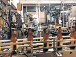  ?? Carrie Antlfinger / Associated Press ?? Trevor Stevens works in the bottling room at Lakefront Brewery in Milwaukee. The brewery is waiting for feds to approve the “My Turn: Chuck” beer label.Russ Klisch, founder and president of Lakefront Brewery, says new releases of beer are on hold because federal regulators are on furlough.