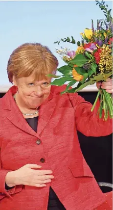  ?? FOTO: SAUER/DPA ?? Danke für die Blumen: Auf dem CDU-Parteitag in Stralsund freute sich Angela Merkel über ihre Wahl. Und ging auf Angriff Richtung SPD.