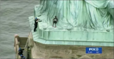  ?? WPIX-TV, VIA AP ?? This image from TV shows two police officers, left, approachin­g protester Therese Okoumou on Wednesday at the Statue of Liberty in New York Harbor.