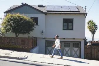  ?? Paul Chinn / The Chronicle 2019 ?? Dorothy Krause walks past her home with solar panels installed on the roof in Oakland last October. A key incentive for rooftop solar panels is being threatened.