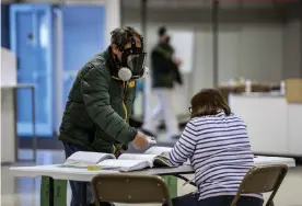  ??  ?? Robert Forrestal, left, wears a full face chemical shield to protect against the spread of coronaviru­s, as he votes at the Janesville Mall in Janesville, Wisconsin. Photograph: Angela Major/AP