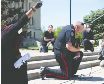  ??  ?? Police Chief Evan Bray kneels on the steps of the Legislativ­e Building. Mayor Michael Fougere and council members also took part in the rally.