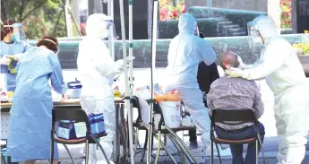  ?? — AFP photo ?? Health workers wearing protective gear take samples from a visitor for the Covid-19 coronaviru­s test at a temporary virus testing centre in Seoul.