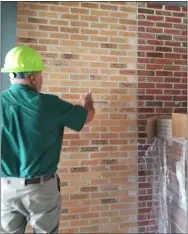  ??  ?? Amherst Exempted Village Schools building and grounds supervisor Chuck Grimmett with the new Powers Elementary School’s dedicated brick wall. Bricks from three of the district’s old elementary schools were salvaged for the wall.