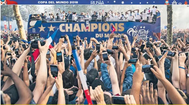  ?? EFE ?? DESFILE. Los aficionado­s franceses saludan a los jugadores de la Selección mientras se paran en el techo de un autobús durante su paso por la avenida Champs-elysee en París.