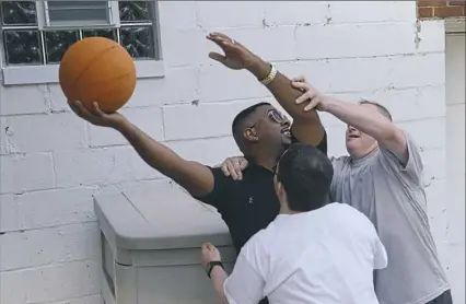  ?? Rebecca Droke/Post-Gazette photos ?? Jason Tessling, 34, front, and Matthew Mittelmeie­r, 49, right, team up against Jovan Harris, a senior direct support profession­al with Emmaus Community of Pittsburgh, as they play basketball after dinner Wednesday at a group home in Mt. Lebanon.