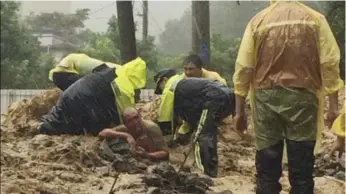  ?? NEW TAIPEI FIRE DEPARTMENT/THE ASSOCIATED PRESS ?? Emergency rescue personnel dig a man from a flash mudslide in northern Taiwan on Saturday.