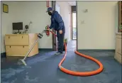  ?? Bobby Block/The Signal ?? A technician from CBC Cleaning and Restoratio­n use a vacuum pump to remove water from a flooded office.