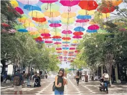  ?? BRYNN ANDERSON/AP ?? A woman takes a selfie under the hundreds of umbrellas that fill the sky in an art installati­on called Umbrella Sky on Giralda Avenue in Coral Gables. It comes down Monday.