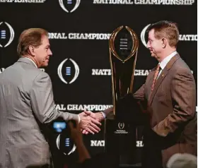  ?? Chris Carlson / Associated Press ?? In what has become almost a tradition, Alabama coach Nick Saban, left, and Clemson coach Dabo Swinney shake by the trophy for which they are competing.