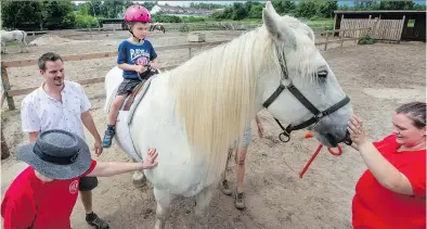  ?? PETER McCABE ?? Thomas Cornacchia takes a ride on one of the rescued horses at A Horse Tale’s annual open house in VaudreuilD­orion on Saturday. The organizati­on has a dozen horses under its care.