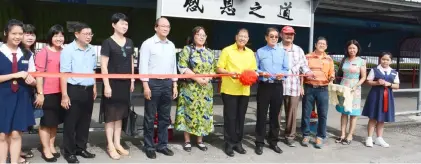  ??  ?? Ting (sixth right), flanked by Tang on his right and Huang, and accompanie­d by teachers and staff of SJK(C) Chung Hua Krokop Miri, cuts the ribbon to officially declare open the new bus stop shed.