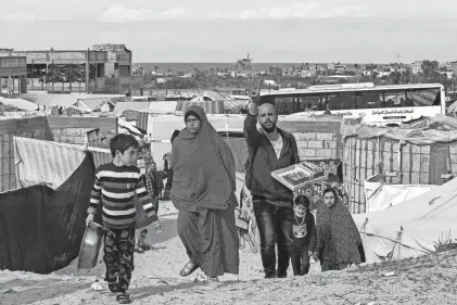  ?? SAID KHATIB/AFP VIA GETTY IMAGES ?? Displaced Palestinia­ns walk through a refugee camp in Rafah, Gaza Strip, near the border with Egypt. Residents on Saturday reported airstrikes and shelling in the north and south, including Rafah – one area where the Israeli army had ordered civilians to evacuate to.