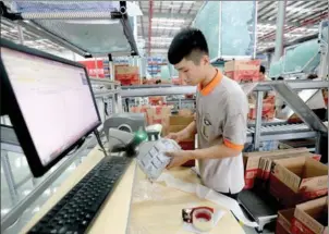  ?? HE GUANG / FOR CHINA DAILY ?? A handler of e-commerce goods scans the barcode on a parcel in one of Cainiao’s smart delivery centers in Guangzhou, Guangdong province.