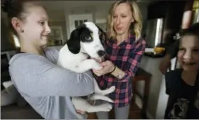  ?? STEVEN SENNE — ASSOCIATED PRESS ?? In this Wednesday, March 29, 2017 photo Morgan Fredette, 13, left, holds the family dog Roscoe as her mother Kate, center right, and brother Lucas, 11, right, play with the dog at their home in Waltham, Mass. The family found the dog through the online...
