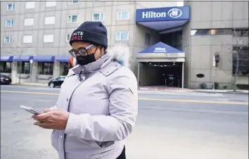  ?? Associated Press ?? Hotel housekeepe­r Esther Montanez looks at her cellphone outside the Hilton Back Bay on Friday in Boston. Montanez refuses to give up hope of returning to her cleaning job at the hotel, which she held for six years until being furloughed since March 2020 due to the COVID-19 virus outbreak. The single mother cannot bear the idea of searching for work that will almost certainly mean earning near the minimum wage.