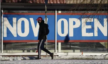  ?? DAVID ZALUBOWSKI — THE ASSOCIATED PRESS ?? A pedestrian in a face covering walks past a sign plastered on the windows of a restaurant to announce that it is open after closure because of the coronaviru­s in Boulder, Colo.