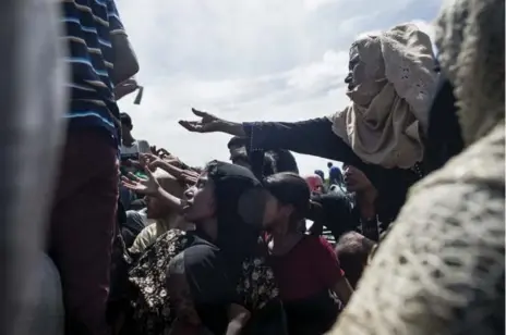  ?? FRED DUFOUR/AFP/GETTY IMAGES ?? Rohingya Muslim refugees from Burma take money from a Bangladesh­i NGO as they board a boat to travel to a camp for refugees.