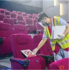  ?? — AFP ?? Workers place signage to block off seats inside a cinema in Manila on Thursday ahead of the reopening of movie houses.