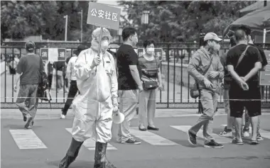  ?? AFP VIA GETTY IMAGES ?? A medical worker spreads the word about the Xinfadi Market in Beijing.