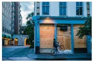  ?? JOHNNY MILANO / THE NEW YORK TIMES ?? A bicyclist passes a boarded up business Wednesday ahead of Hurricane Florence’s expected arrival in Charleston, S.C.