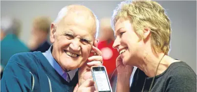  ??  ?? TV presenter Sally Magnusson listens to her iPod with Harry Massie from Edinburgh. There is growing evidence that listening to favourite songs from the past can improve the mood of people with dementia and help their ability to understand.