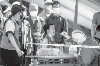  ?? MARK SCHIEFELBE­IN/AP ?? A worker clad in a protective suit swabs a child’s throat for COVID-19 testing Wednesday in Beijing.