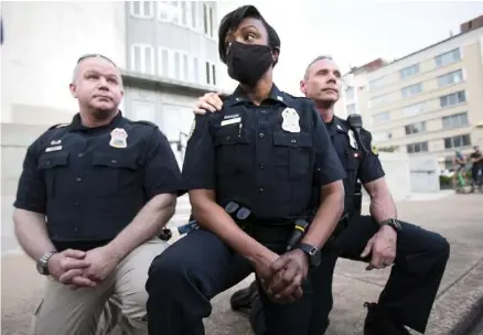  ?? STAFF PHOTO BY TROY STOLT ?? Three Chattanoog­a Police Department officers take a knee after a crowd of protesters asked them to do it in a show of solidarity as they protested Monday night for an end to police brutality.