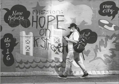  ?? RICH PEDRONCELL­I/AP ?? A man passes a colorful panel painted with the message “Mission: Hope on K Street,” in Sacramento, Calif., on April 7.