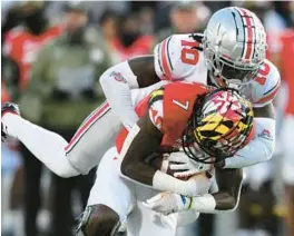  ?? NICK WASS/AP ?? Ohio State cornerback Denzel Burke tackles Maryland wide receiver Dontay Demus Jr. during Saturday’s game in College Park. Demus caught five passes for 67 yards in his best game of the season.