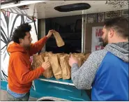  ?? ED WHITE — THE ASSOCIATED PRESS ?? Hassan Musselmani, left, and Andrew Quatrine hand out free meals on the eastside of Detroit on Tuesday. Musselmani’s food truck, The Drunken Rooster, is idle during the coronaviru­s pandemic, so he figured it was a good way to distribute food prepared by Rising Stars Academy, a school that specialize­s in culinary arts in Center Line.