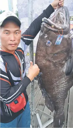  ??  ?? Ng Cher How with his winning catch, a grouper weighing a whopping 61.68kg.