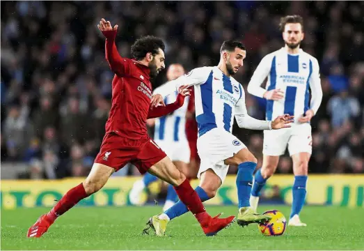  ?? — Reuters ?? That’s mine: Brighton’s Martin Montoya (centre) vying for the ball with Liverpool’s Mohamed Salah during the English Premier League match at the American Express Community Stadium on Saturday.