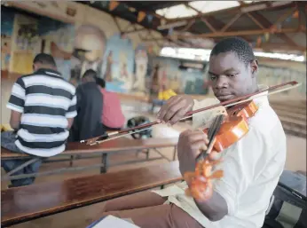  ?? PICTURE: EPA ?? A member of the youth orchestra, Ghetto Classics, tunes the strings of a violin before their weekly practice at St John’s Roman Catholic Church in Korogocho slum, in Nairobi, Kenya, this week. Started in 2008 as a joint project with the Art Of Music...