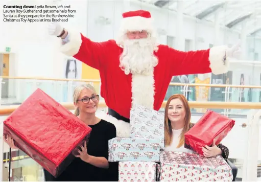  ??  ?? Counting down Lydia Brown, left and Lauren Roy-Sutherland get some help from Santa as they prepare for the Renfrewshi­re Christmas Toy Appeal at intu Braehead