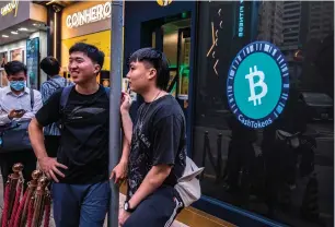  ?? — AFP ?? People stand outside a cryptocurr­ency exchange in Hong Kong. In the UAE, crypto assets have emerged as the predominan­t investment choice among retail investors.