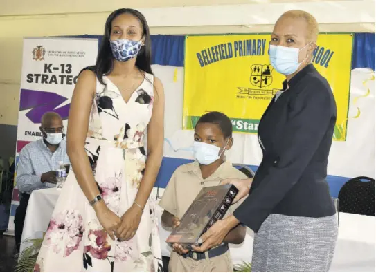  ?? (Photo: Gregory Bennett) ?? Education Minister Fayval Williams (right) is joined by Manchester Central Member of Parliament Rhoda Crawford (left) in presenting a tablet to Bellefield Primary School grade 4 student Dexroy Anderson.